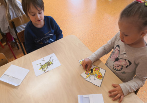 dzieci przy stolikach układają puzzle z owadami żyjącymi na łące