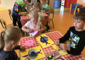 dzieci przy stolikach wykonują prace plastyczną nt. Motyk z kół origami
