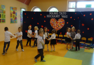 dzieci tańczą w parach na tle dekoracji "Mamo, tato kocham Was"