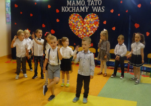 dzieci tańczą na tle dekoracji "Mamo, tato kocham Was"