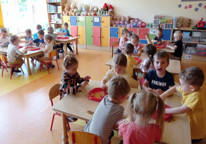 dzieci przy stolikach układają obrazki z makaronów