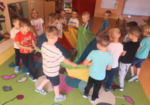 Dzieci uczestniczą w zabawie integracyjnej z wykorzystaniem chusty animacyjnej.
