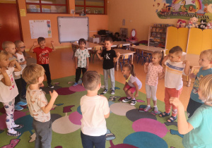 Dzieci stoją w kole pokazując ruchy do piosenki.