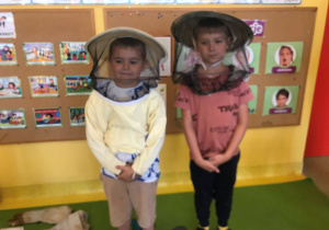 Dwóch chłopców pozuje w strojach pszczelarza.
