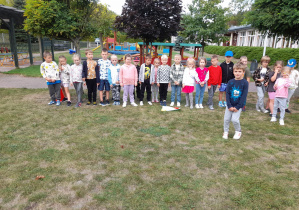 Dzieci stoją w ogrodzie przedszkolnym na napisie Start i przygotowują się do biegu.