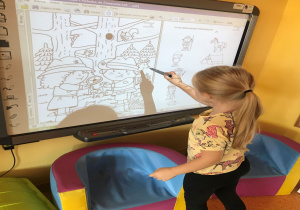 Dziewczynka wskazuje na rysunek znajdujący się na tablicy interaktywnej.