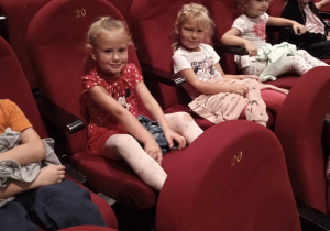 Dzieci siedzą w fotelach kinowych.