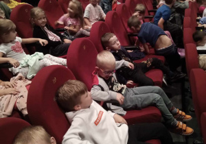 Dzieci siedzą w fotelach i przygotowują się do oglądania spektaklu.