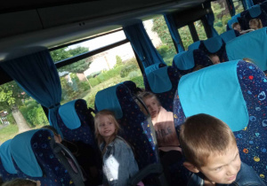 Przedszkolaki siedzą w fotelach w autobusie.
