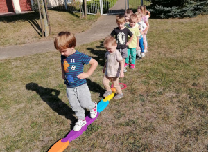 Dzieci chodzą po linii prostej stopa za stopą utrzymując równowagę.