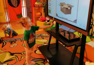 Dziewczynka wskazuje gdzie na monitorze interaktywnym jest miś.