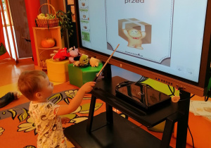 Chłopiec wskazuje gdzie na monitorze interaktywnym jest miś.