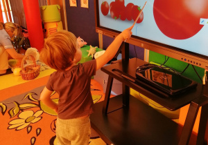 Chłopiec wskazuje wskaźnikiem pomidora na monitorze interaktywnym.