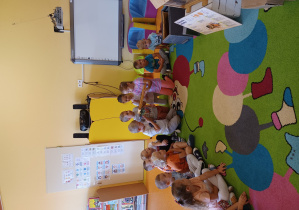 Dzieci siedzą na dywanie i oglądają ramki z miodem.