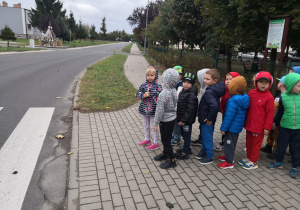 Przedszkolaki są na spacerze, zatrzymały się przed przejściem dla pieszych.