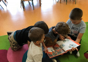 Przedszkolaki oglądają książkę.