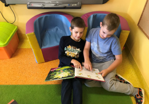 Dwóch chłopców ogląda książkę.