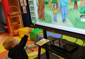 Chłopiec wskazuje na wiewiórkę na ekranie interaktywnym.