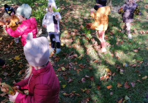 Dzieci są na spacerze w parku, trzymają w ręcach liście.