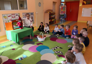 Dzieci siedzą na dywanie, Pani Maria prezentuje im przyniesioną maskotkę Krasnala Hałabały.