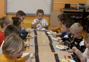 Przedszkolaki jedzą zrobione przez siebie owocowe koreczki i szaszłyki.