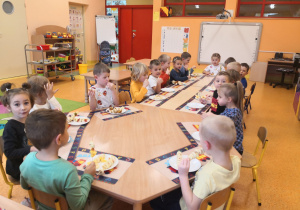Przedszkolaki jedzą zrobione przez siebie owocowe koreczki i szaszłyki.