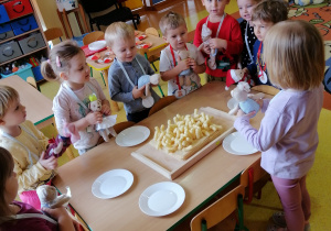 Przedszkolaki degustują miód z chrupkami kukurydzianymi.