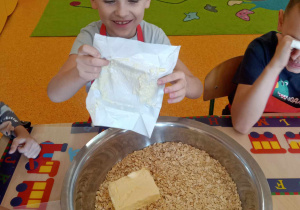 Chłopiec wrzuca masło do miski.