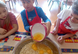 Chłopiec dodaje jajka miski.