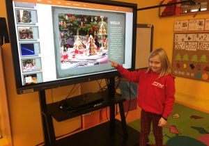Dziewczynka wskazuje na ekran tablicy interaktywnej.