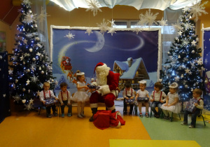 Mikołaj rozdaje dzieciom prezenty.