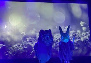 Na zdjęciu są dwie osoby występujące na scenie w masce niedźwiedzia i zająca.