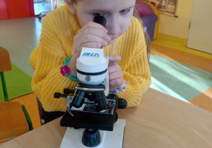 Dziewczynka korzysta z mikroskopu.