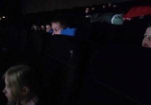 Dzieci siedzą w kinie i oglądają bajkę.