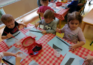 Dzieci wykonują prace plastyczną "Ptaszek w karmniku".