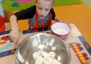 Chłopiec wkłada do miski jogurt naturalny Skyr.