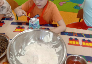 Chłopiec wsypuje do miski sodę oczyszczoną.