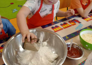 Chłopiec wsypuje mąkę do miski.