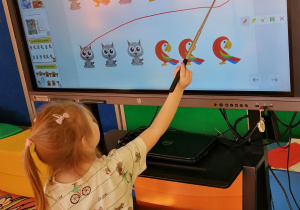 Dziewczynka wskazuje zwierzątko na ekranie interaktywnym.