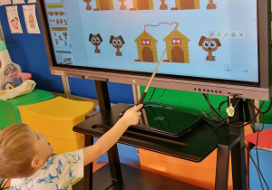 Chłopiec wskazuje zwierzątko na ekranie interaktywnym.