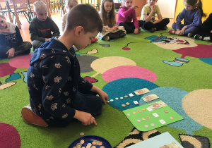 Dzieci wykonują ćwiczenia matematyczne z banknotami i monetami.
