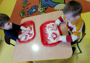 Dzieci rysują palcem w mące.