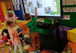 Dziewczynka i chłopiec ustalają kolejność zdarzeń na tablicy interaktywnej.