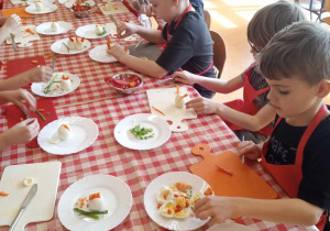 Dzieci wykonują kompozycje wielkanocne z jajek i warzyw.
