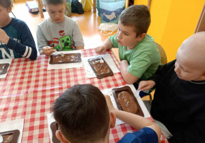 Dzieci rozprowadzają czekoladę po foremce.