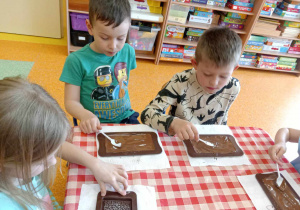 Dzieci rozprowadzają czekoladę po foremce.