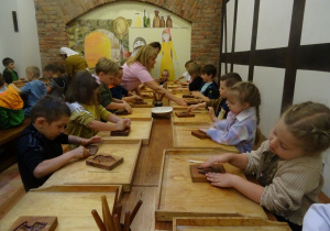 Przedszkolaki wkładają ciasto do foremek na pierniki.