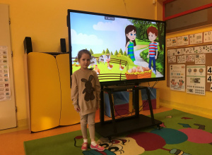 Dziewczynka stoi przy tablicy interaktywnej.