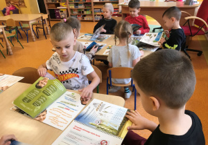 Dzieci przeglądają książki o produktach ekologicznych.
