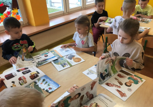Dzieci przeglądają książki o produktach ekologicznych.